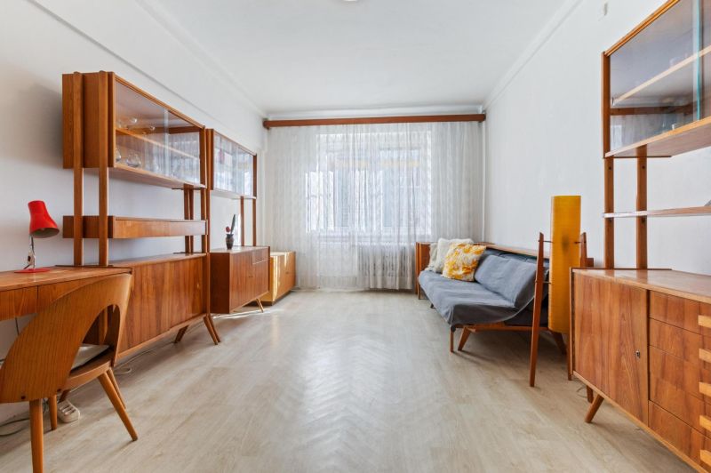 A living room in a 3-room apartment with a wooden decor floor and retro furniture.