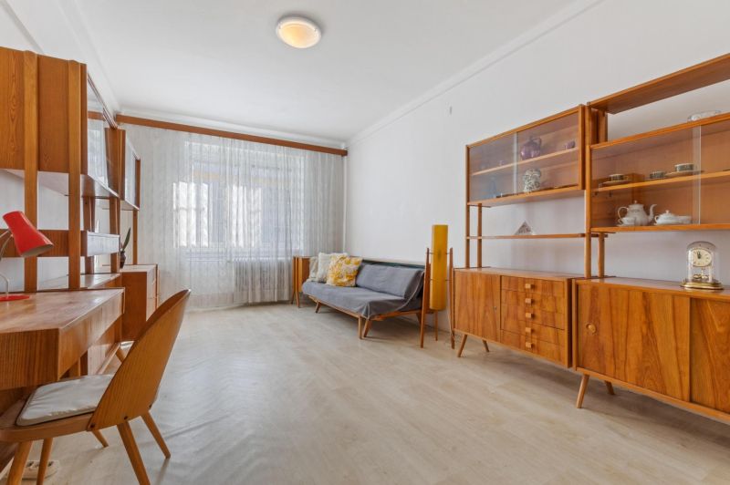 A room in a 3-room apartment with retro furniture and a wooden decor floor.