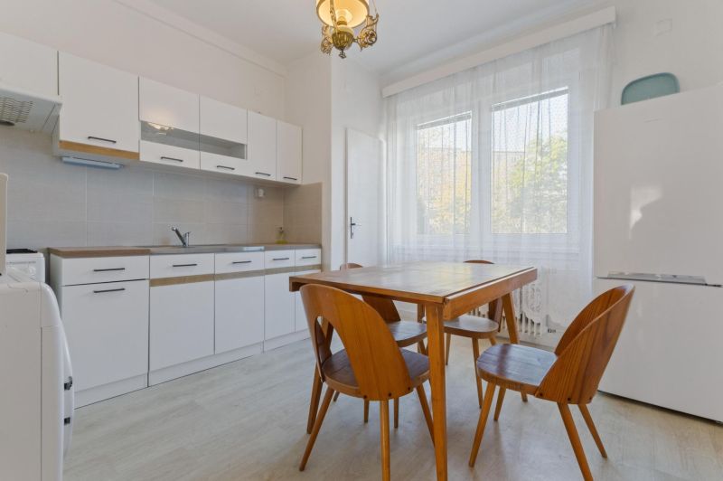 A kitchen in a 3-room apartment with a dining table and chairs, floor with wooden decor.