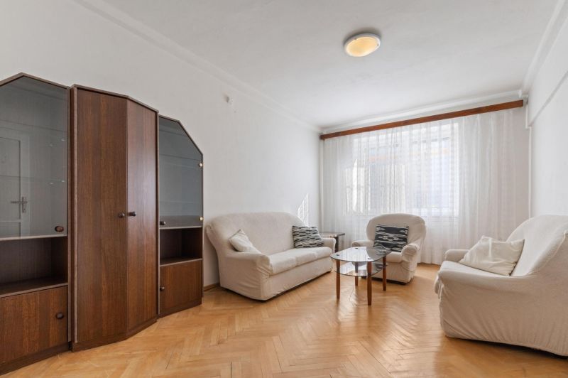 Living room with white sofas, a display cabinet, and a wooden decor floor in a three-room apartment.
