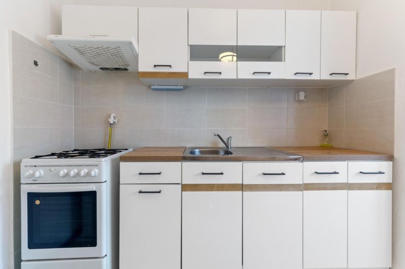 A kitchen in a 3-room apartment with white cabinets and a gas stove.