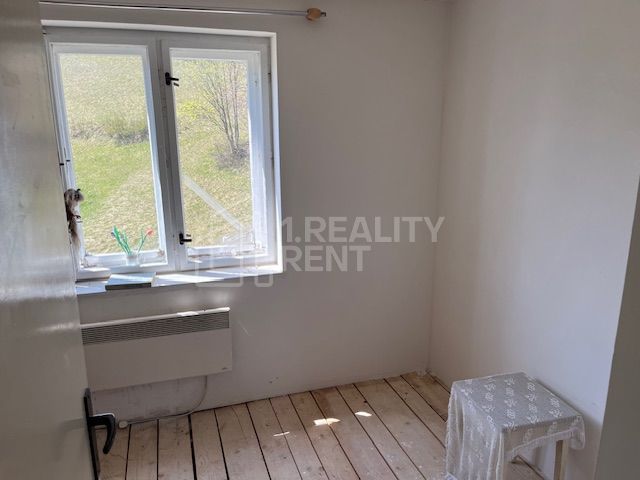 A white room in a family house with a wood-patterned floor and a view of the garden.