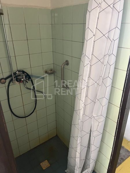 A shower corner with tiles and a curtain in the bathroom of a family house.