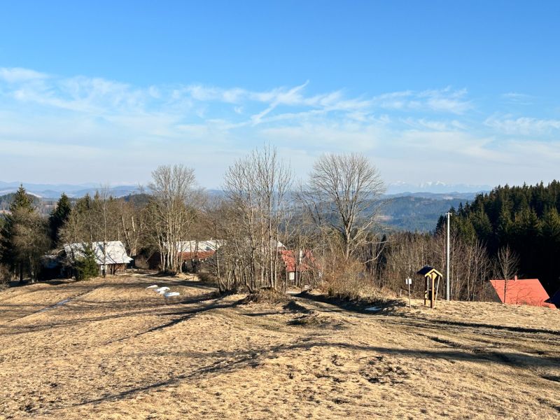 A view of family houses in Korňa surrounded by nature and forests, clear skies.