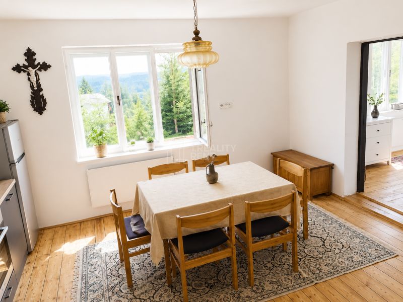 Dining room in a family house with a wood-patterned floor and a view of the forest.