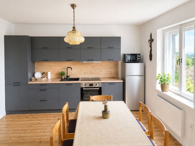 A kitchen in a family house with a wooden decor and dark gray kitchen cabinets, light streaming through the window.