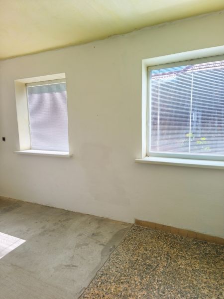 Walls and windows of a room with a concrete floor and blinds in a family house.