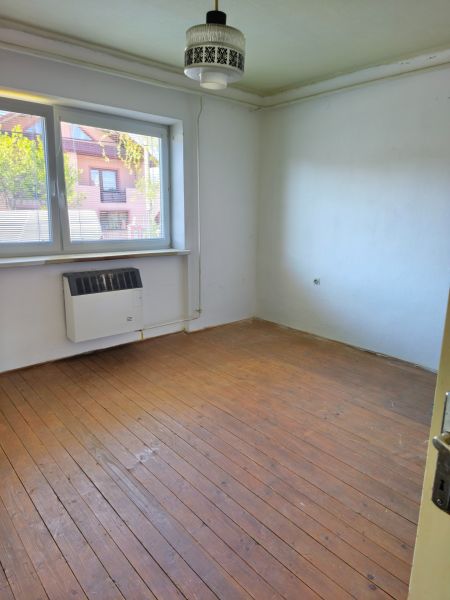 A room in a family house with a window, a light fixture, and a floor with a wooden decor.