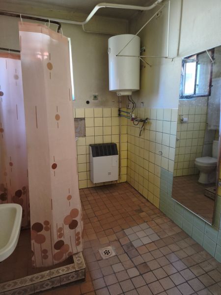 Bathroom with a gas heater in a family house, with a pink shower curtain and tiles.