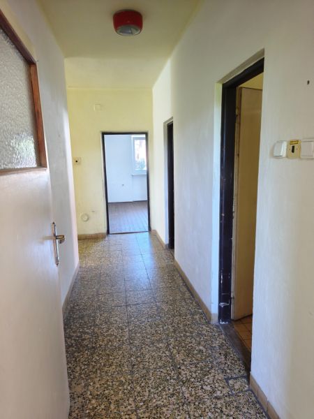 A hallway with light walls, tiles, and doors in a family house.