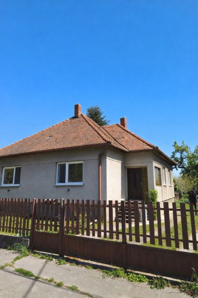 A family house in Zlaté Moravce with a sloped roof and a fence in the foreground.
