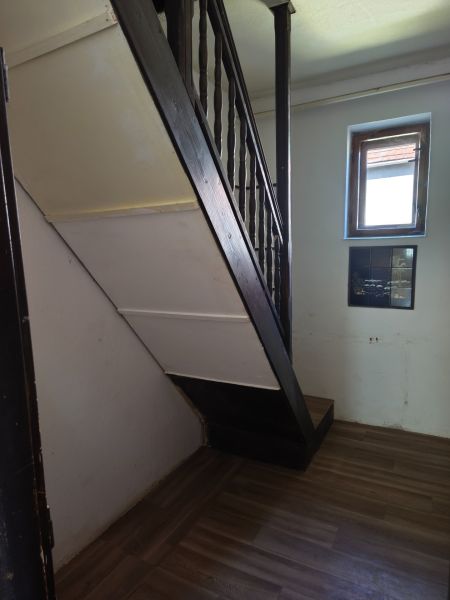A staircase in a family house with a wooden decor floor and a small window.