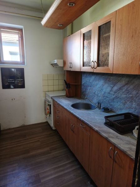 A kitchen in a family house with wooden cabinets and a floor with a wooden design.