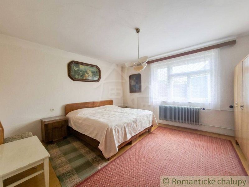 Bedroom in a family house with carpets, a bed, and a painting on the wall.