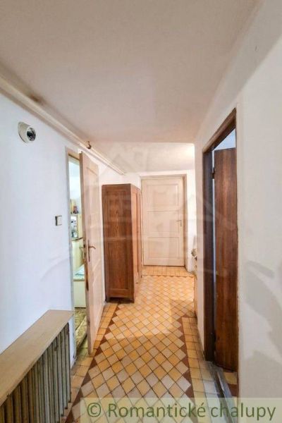 A hallway in a family house with rustic tiles and wooden furniture.