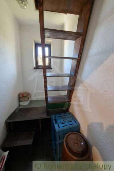 Attic stairs in a family house with a wood decor and a window.