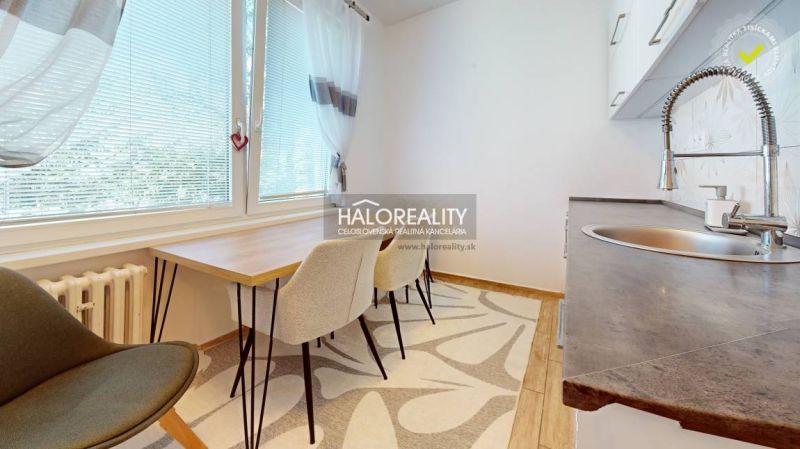 A kitchen in a 2-room apartment with a dining table and a floor with a wooden decor.