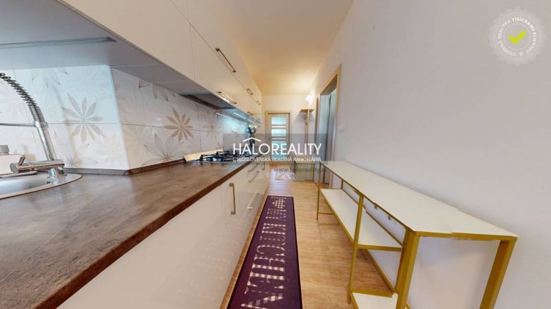 A kitchen with white cabinets and decorative tiles in a two-room apartment.