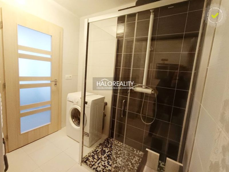 A bathroom in a 2-room apartment with a washing machine and a shower.