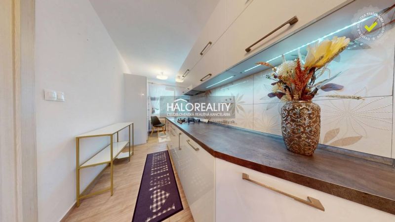 A kitchen unit with decorative tiles, a shelf, and a wooden decor floor in a 2-room apartment.