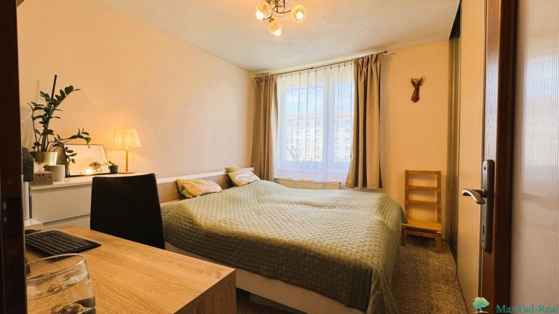 A bedroom in a 3-room apartment with a double bed and a window with curtains.