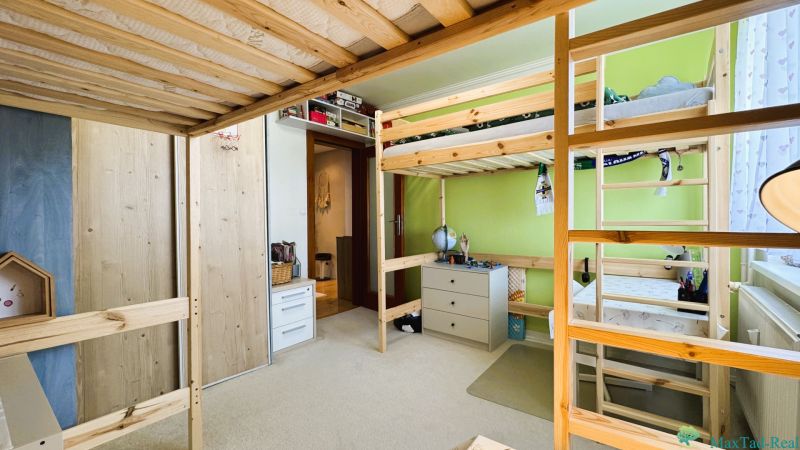 Children's room in a 3-room apartment with a wooden bunk bed and a green wall.