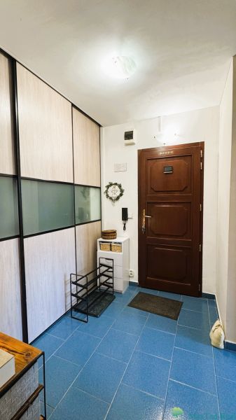 The hallway of a 3-room apartment with dark doors, blue tiles, and a built-in wardrobe.