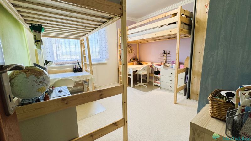A room with bunk beds, desks, and carpeted flooring in a 3-room apartment.