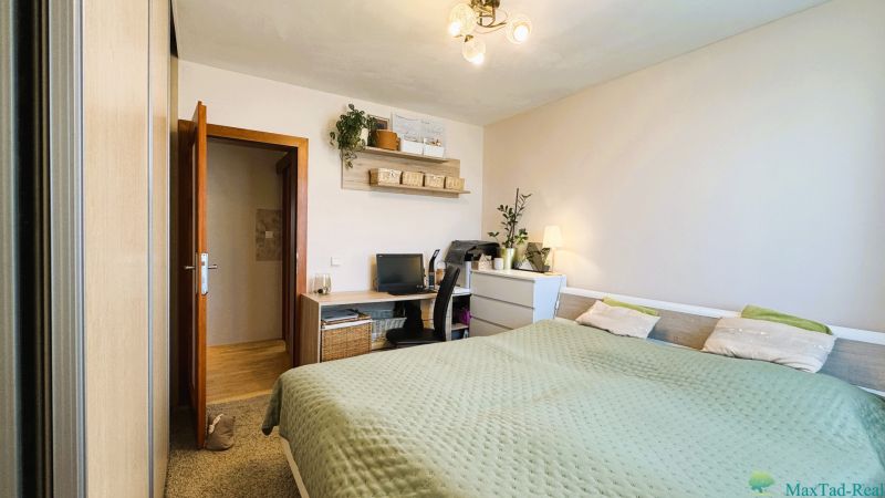 A bedroom in a 3-room apartment with a desk and decorative plants.