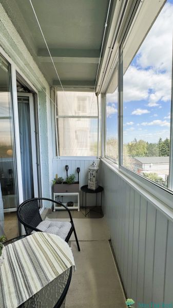 A glazed balcony in a 3-room apartment with seating and a view of nature.