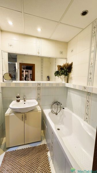 Bathroom with a sink and a bathtub in a 3-room apartment, decorative tiles.