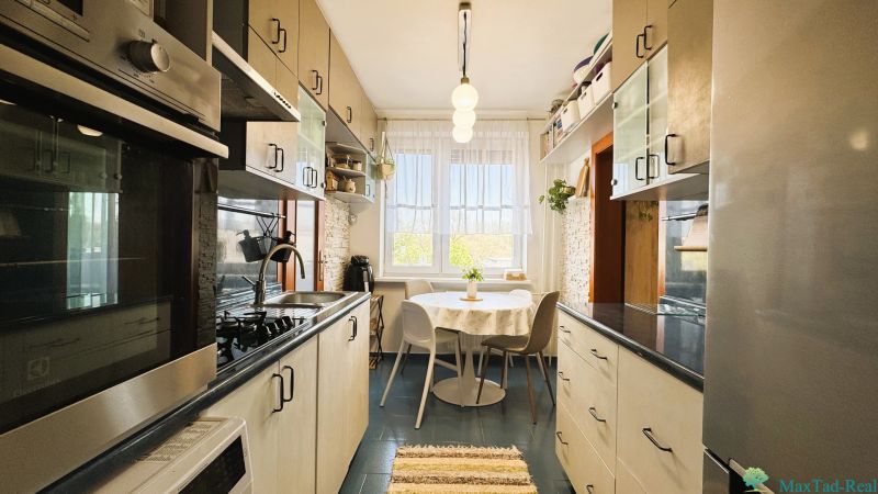 A kitchen in a 3-room apartment with dining, white cabinets, and appliances.