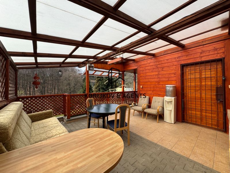 Covered terrace of the cottage in Svinica with seating and a forest view.