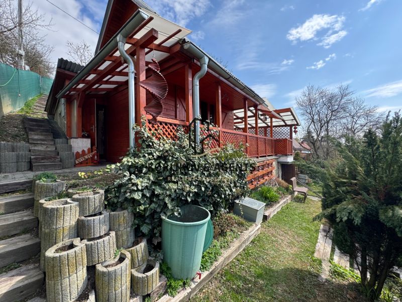 Wooden cottage in Svinica with a terrace, garden, and outdoor staircase on a green area.