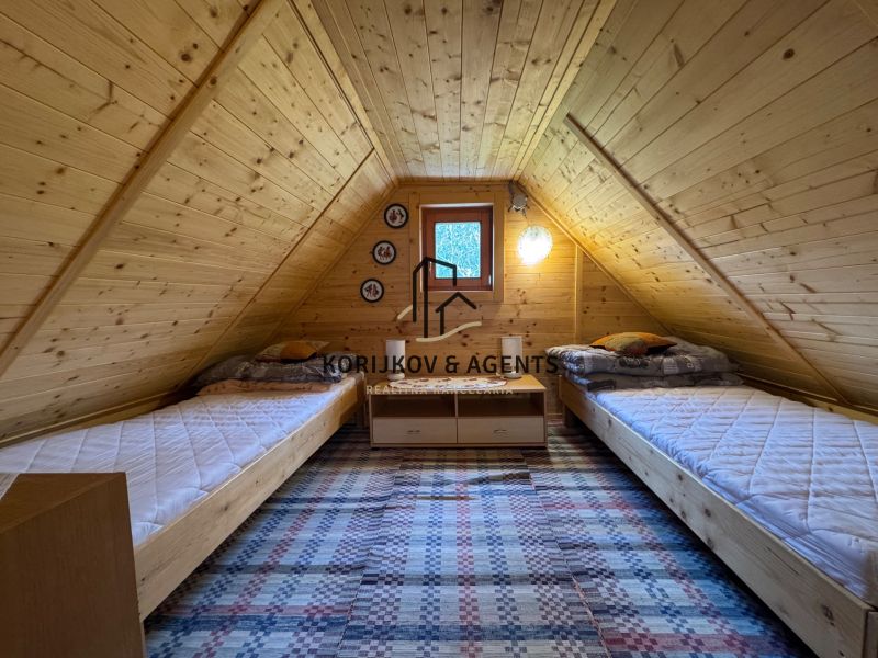 An attic room in a cottage with two beds and wooden decor.