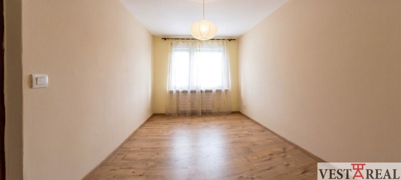 A room with a wooden decor floor and curtains in a 3-room apartment.