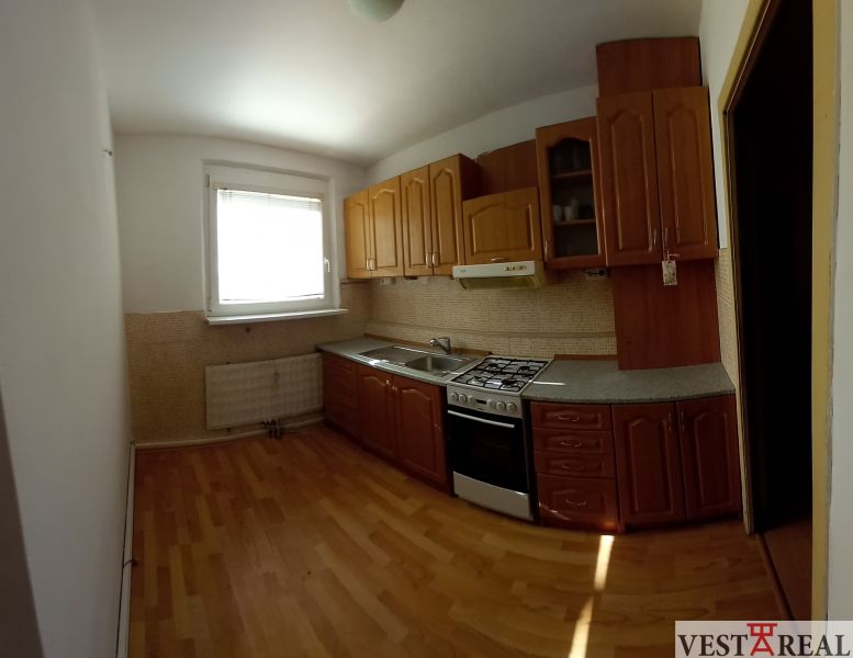 A kitchen in a 3-room apartment with a kitchen unit and a floor with a wooden decor.