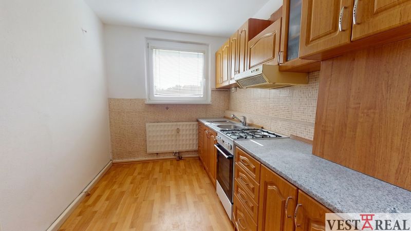 A kitchen in a 3-room apartment with a kitchen unit and a floor with a wooden decor.