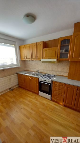 A kitchen with wooden cabinets and a wood-patterned floor in a 3-room apartment.