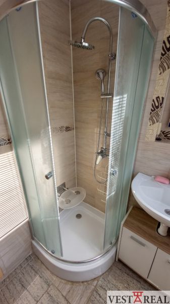 A shower enclosure with sliding doors next to the sink in a 3-room apartment.