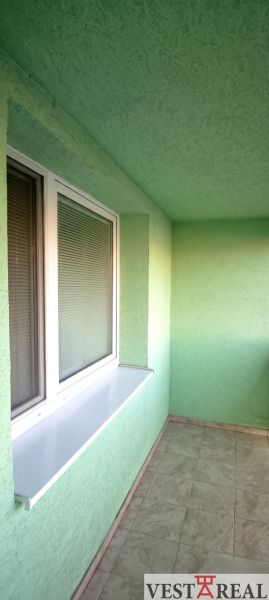 Glazed loggia in a 3-room apartment with tiles and a green wall.