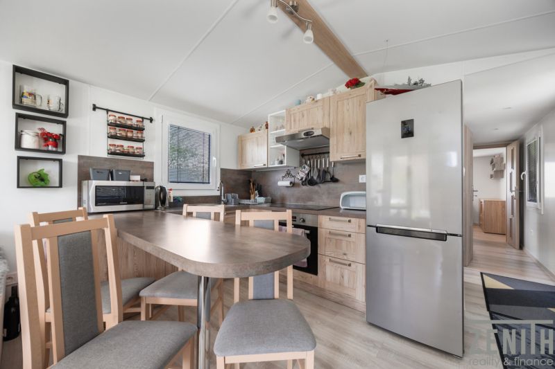 A kitchen in a cabin with wooden decor, a dining table, and modern appliances.