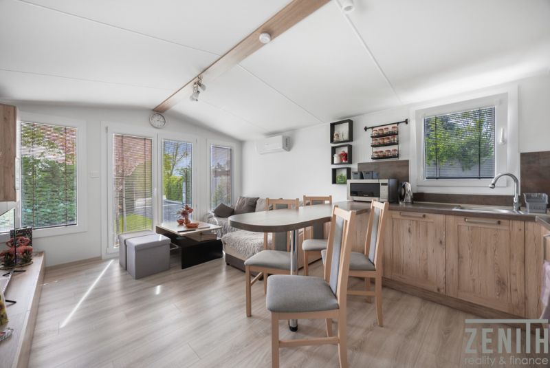 Interior of a cabin with wood-decor flooring, kitchen, and dining area.