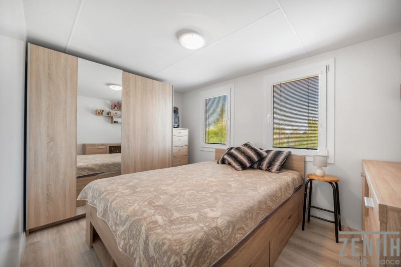 A bedroom in a cabin, with a bed, a wardrobe, and a floor with a wooden decor.