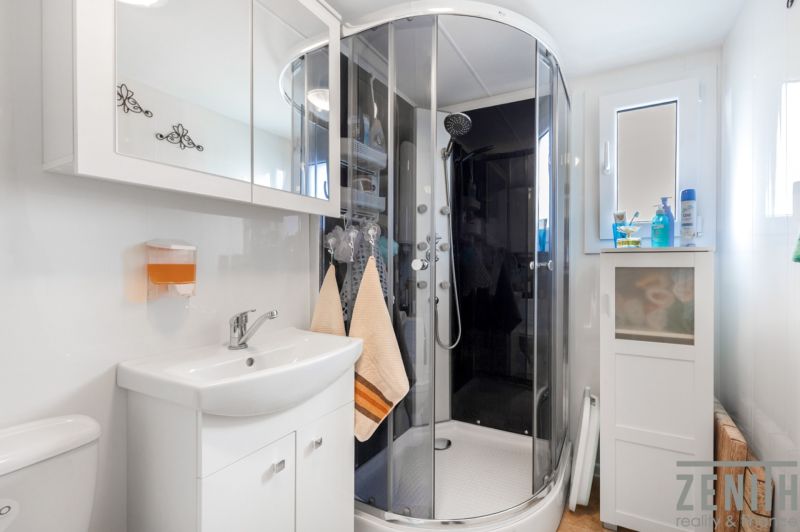 Bathroom in a cabin with a modern shower, sink, and storage space.