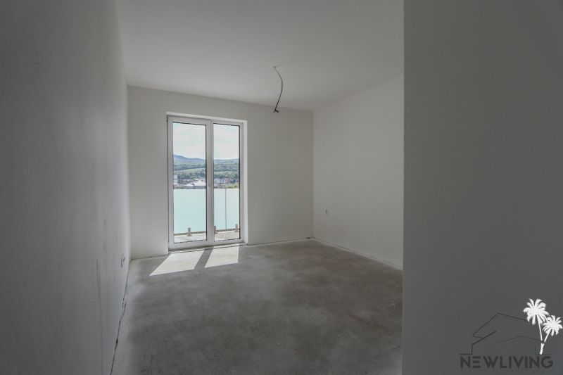A room in a 2-room apartment with a large window without flooring with a wooden decor.