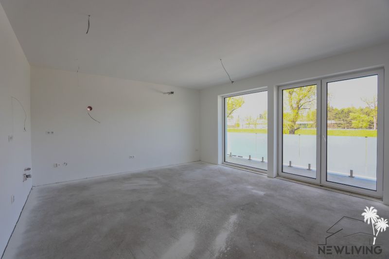 Empty room in a 2-room apartment with large windows and a view of the garden.