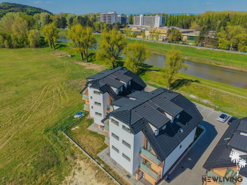 Apartment building with a black roof by the river on Moravanská Street in Banka.