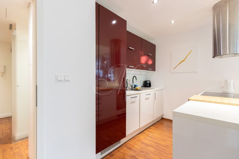 A kitchen in a 2-room apartment with white cabinets and a wooden decor floor.