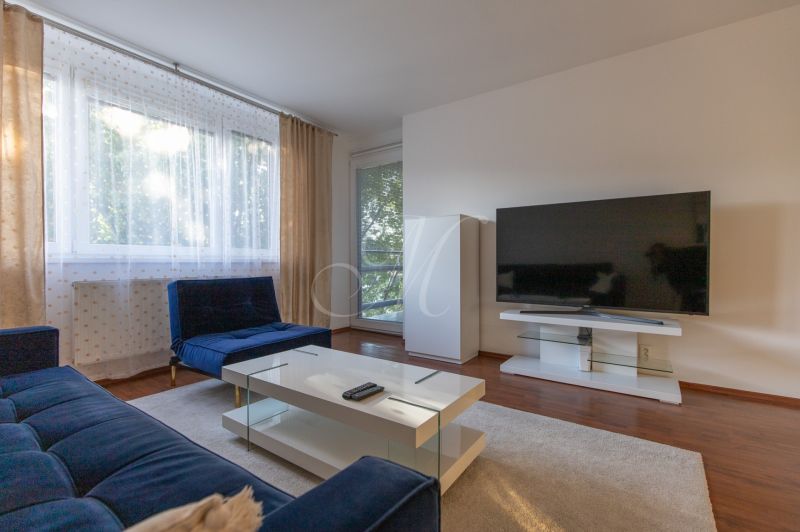 Living room with a sofa, television, and wooden decor flooring in a 2-room apartment.